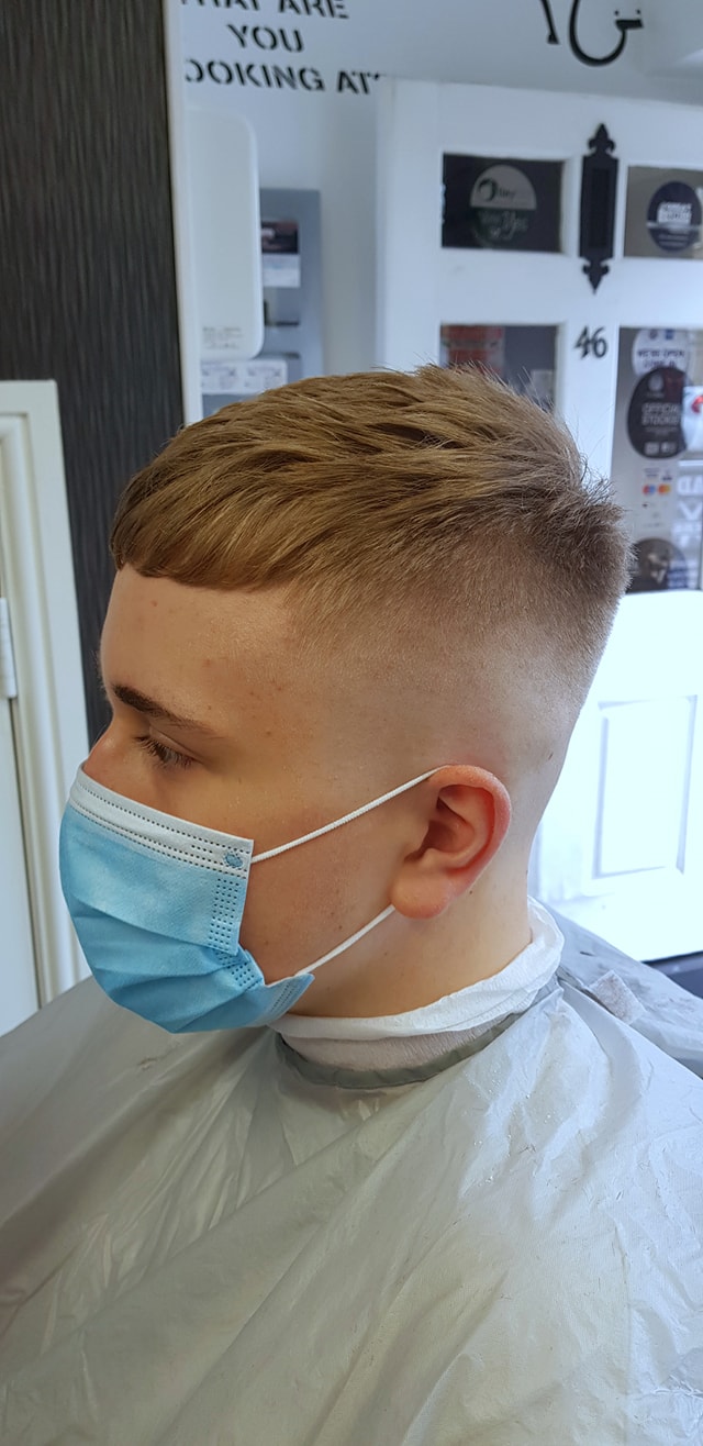 A finished short haircut with a neatly blended fade at Grade 1